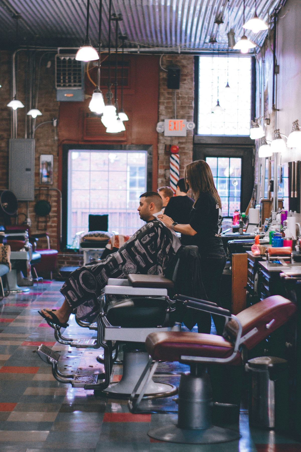 Vintage inspired Aura Barbershop interior with leather chairs, brick walls, and tall windows