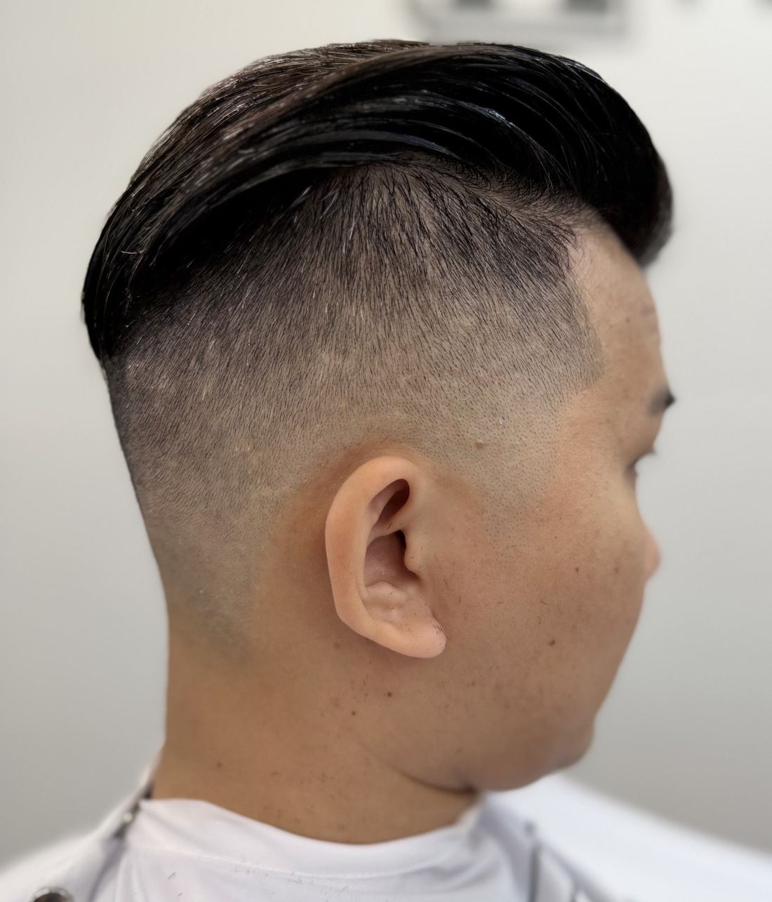 Glossy slicked side part with a low fade